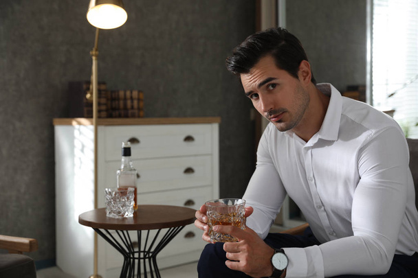 Man near table with whiskey at home - Fotoğraf, Görsel