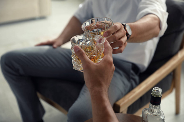 Young men drinking whiskey together at home, closeup - Photo, image