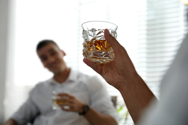 Young men drinking whiskey together at home - Foto, immagini
