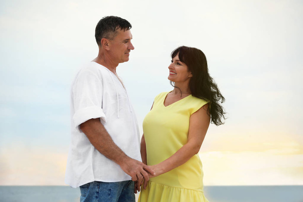 Happy mature couple spending time together on sea beach at sunset - Photo, Image