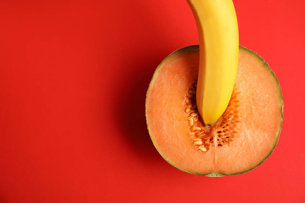 Flat lay composition with fresh banana and melon on red background, space for text. Sex concept - Foto, immagini