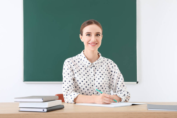 Portrait of young female teacher in classroom - Φωτογραφία, εικόνα
