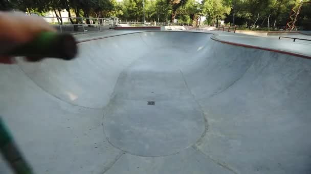 child rides scooter along grey large pool in skate park - Filmati, video