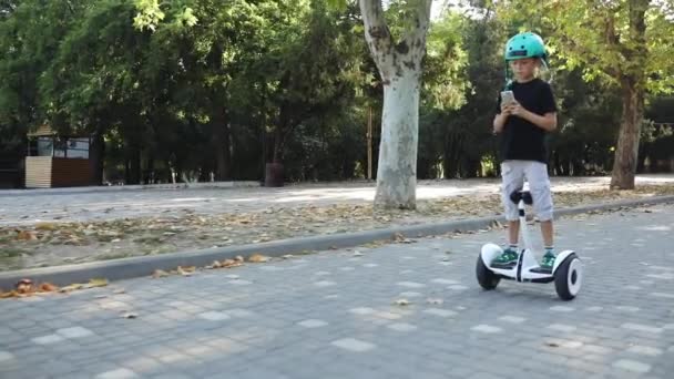 boy rides self-balancing segway and plays on smartphone - Materiał filmowy, wideo