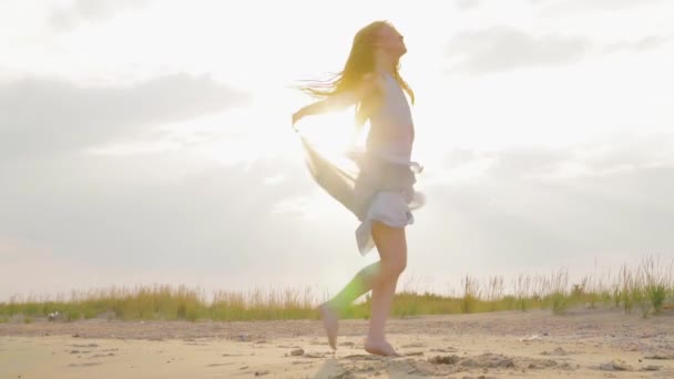 Ανέμελη γυναίκα που χορεύει στο ηλιοβασίλεμα στην παραλία της θάλασσας. Το κορίτσι γυρίζει. Θηλυκότητα στο ηλιοβασίλεμα. Αργή κίνηση. - Πλάνα, βίντεο