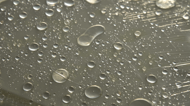Těsné zvětšení dešťových kapek různých velikostí na povrchu pokrytých lepiným filmem. Koncepce vlhkosti a vlhkosti - Záběry, video