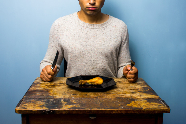Nuori mies, jolla on kanankoipi syötävänä.
 - Valokuva, kuva