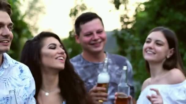 Zbliżenie szczęśliwych młodych przyjaciół bawiąc się razem picie piwa i okulary klinujące - Materiał filmowy, wideo