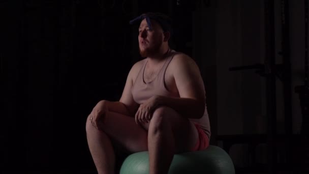 Koncepció túlsúlyos kövér ember egy rózsaszín részt a fitness és a súlyzók Fit labdát a tornateremben - Felvétel, videó