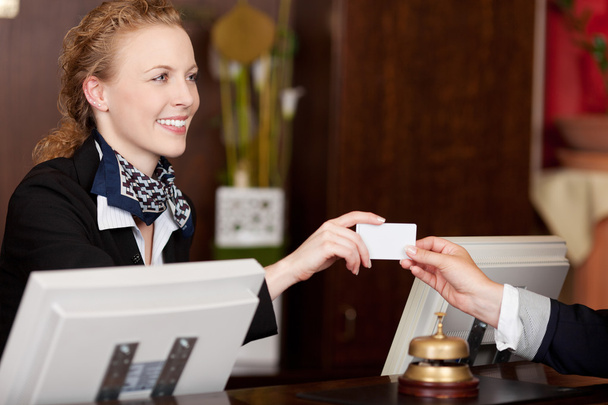 Smiling receptionist handing over a card - 写真・画像