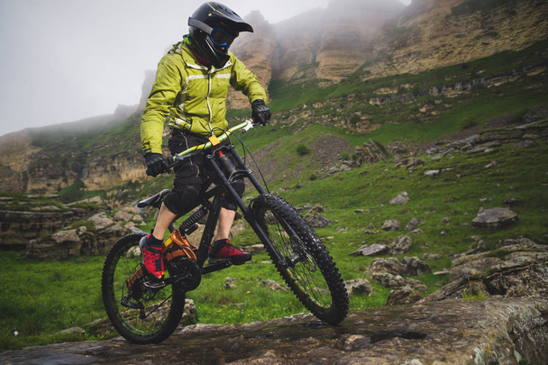Boczny kąt widzenia częściowo człowiek na rowerze górskim podróżuje po skalistym terenie na tle pochmurno nieba i epickie skały. Koncepcja roweru górskiego i MTB Downhill - Zdjęcie, obraz
