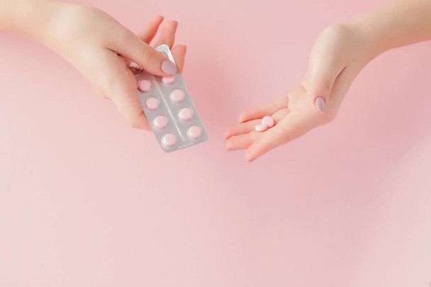 Pink pills tablets in the woman hand on pink background. Top view. Flat lay. Copy space. Medicine concept - Foto, afbeelding