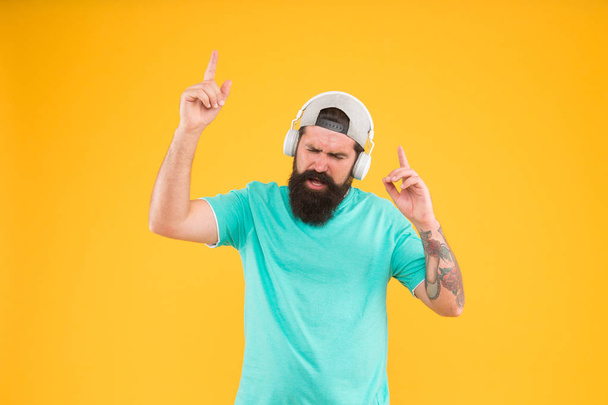 New disco party hit. DJ man on yellow background. Unshaven guy enjoying tune playing at DJ party. Bearded man listening to music in DJ headphones. Hipster using wireless headset for DJ disco - Foto, Imagem