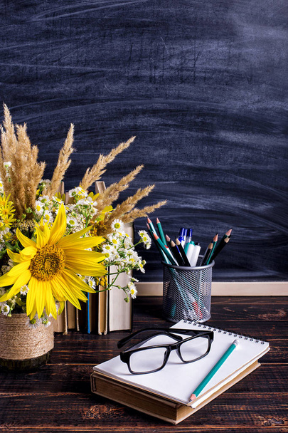 Books, glasses, markers and a bouquet of flowers in a vase on white board background. Concept for teachers day and first September. Copy space. - Фото, зображення