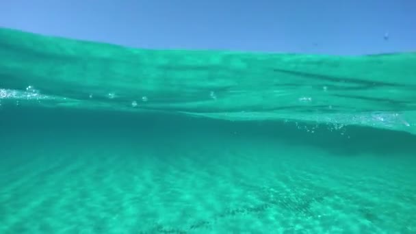 Slow Motion, Half Underwater, Pov: Νεαρό αρσενικό τουριστικό κολύμπι προς τις ηλιόλουστες ακτές της όμορφης Σαρδηνίας. Εντυπωσιακή θέα του εντυπωσιακού ιταλικού νησιού ενώ κολυμπούν στον γαλαζοπράσινο ωκεανό. - Πλάνα, βίντεο