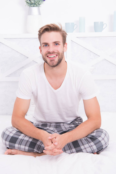 Good morning. Guy happy sit on bed. Man hipster in morning. Asleep and awake. Comfortable relax. Smiling guy wear pajamas at home. Cheerful positive energy. Handsome man enjoy his perfect morning - Foto, afbeelding