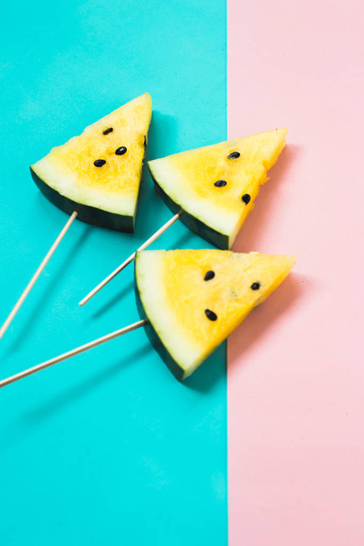 drie driehoekige roomijs plakjes op een stok van rijpe gele watermeloen - Foto, afbeelding