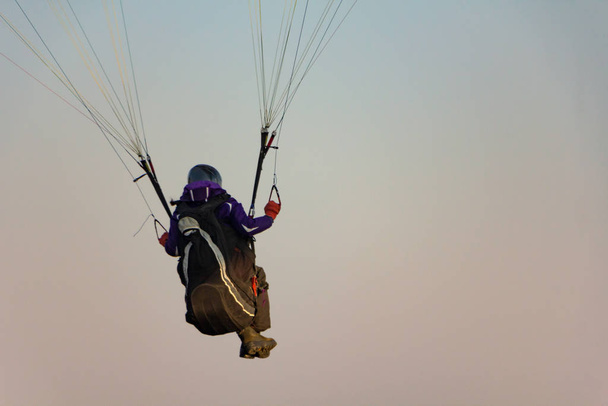 Paraglider prepares to fly in the open air against the sunset sky. Parachute in the backpack outdoors - Photo, Image