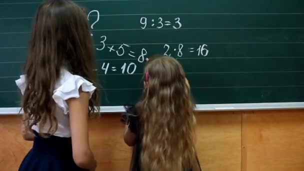 kis iskolás pokes ujját a munkát írt a táblán mellett az idősebb diák - Felvétel, videó