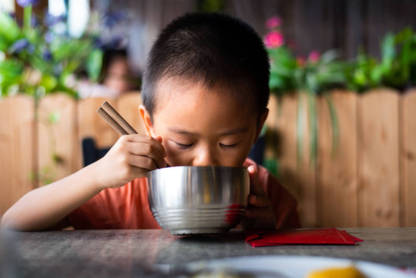 Niño asiático almorzando en el restaurante
 - Foto, Imagen