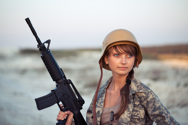 Young beautiful female soldier dressed in a camouflage with a ri - Photo, Image