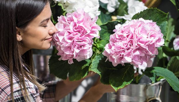 Young girl enjoying a hydrangea flower in a flower shop - Photo, Image