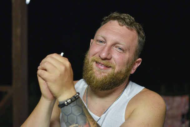 Un homme à la barbe rouge fume une cigarette électronique
. - Photo, image