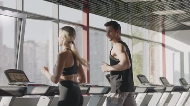 Running couple training cardio exercise on treadmill machine in fitness center - Felvétel, videó