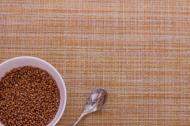 Bowl of raw buckwheat on granny background, top view. Space for text - Photo, Image