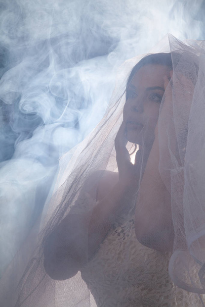 Portrait of the beautiful bride against a light indoors in the smoke - Foto, afbeelding