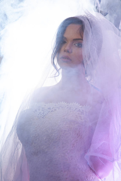 Πορτρέτο της όμορφης νύφης σε ένα φως σε εσωτερικούς χώρους στον καπνό - Φωτογραφία, εικόνα