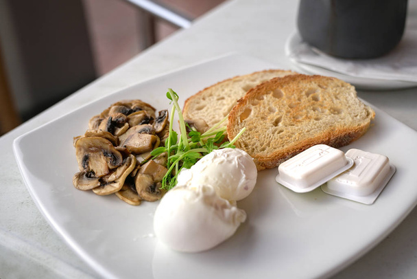 Healthy breakfast with poached eggs, mushrooms and toast bread - 写真・画像