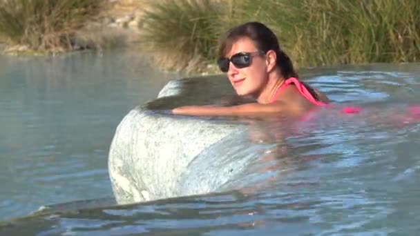 Portret: Młoda kobieta uśmiecha się podczas kąpieli w gorącej wodzie termalnej w fajne spa odkryty. Wesoły Kaukaska dziewczyna relaks w łaźni termalnych ożywczy w Toskanii. Kobiece turystycznych w naturalnych basenach. - Materiał filmowy, wideo