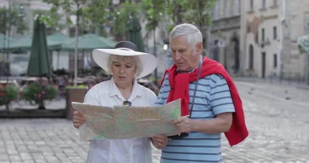 Senior mannelijke en vrouwelijke toeristen staan met een kaart in handen op zoek naar route - Video
