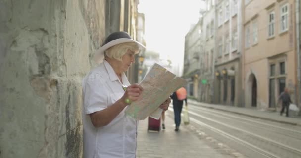 Senior női turizmus feltárása város egy térképet a kezében. Keresi az útvonalat - Felvétel, videó