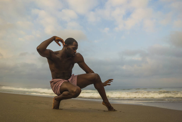 contemporary dance choreographer and dancer doing ballet beach workout . a young attractive and athletic black African American man dancing in dramatic performance  - Fotoğraf, Görsel