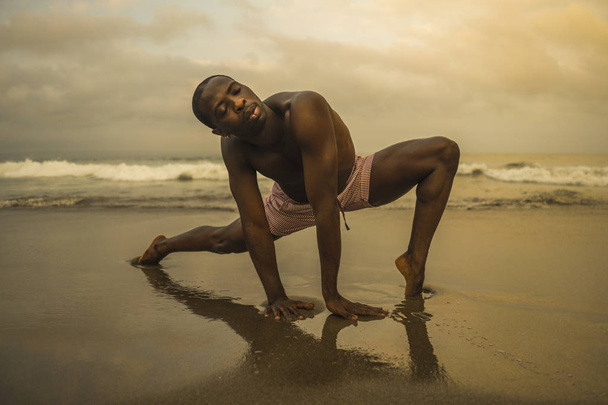dramatic contemporary dance choreographer doing ballet beach workout, young attractive and athletic afro black American man dancing on sunrise  - Foto, Imagem