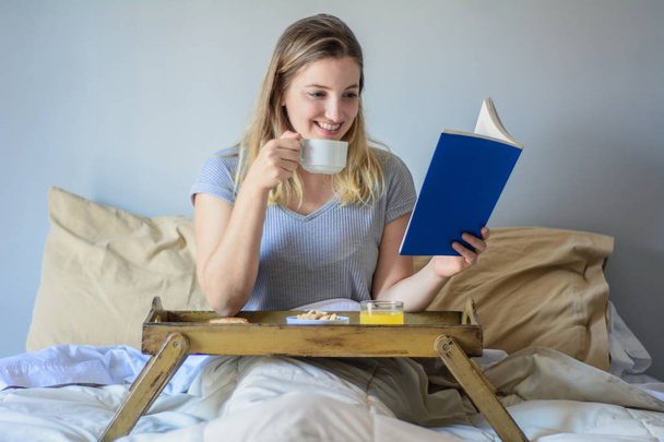 Woman reading a book and having breakfast. - Φωτογραφία, εικόνα
