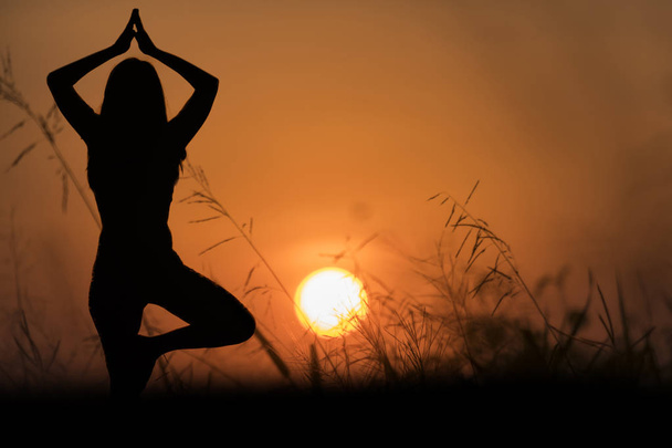 Silhouet Asia vrouw yoga op zonsondergang. - Foto, afbeelding
