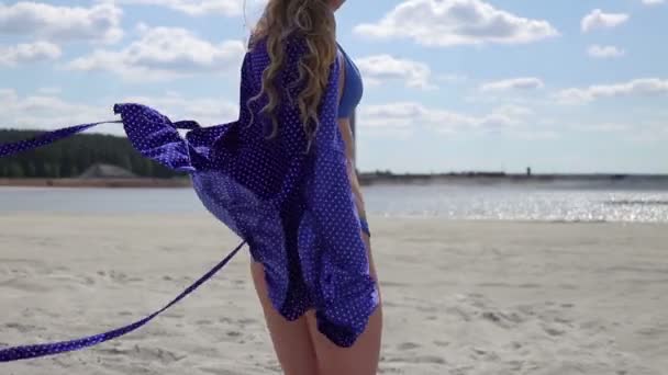 若い女性が手を上げて歩き、軽いスタイリッシュな水着を回す - 映像、動画