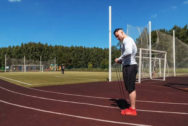 athletic man at the stadium with a rope. Healthy lifestyle. Sport activities on the street - Fotoğraf, Görsel