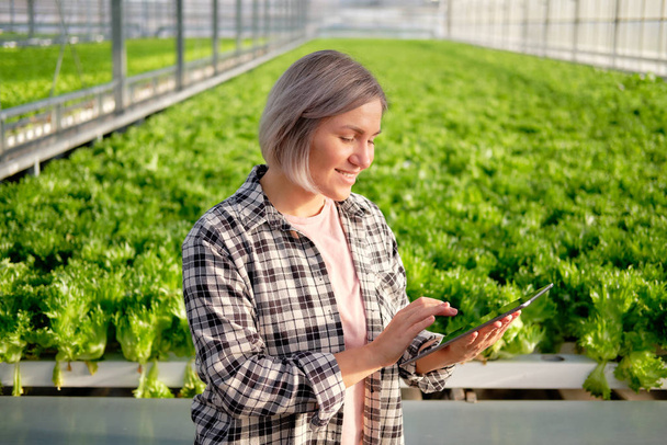 Young Woman Using or Playing Tablet in Greenhouse - Photo, Image
