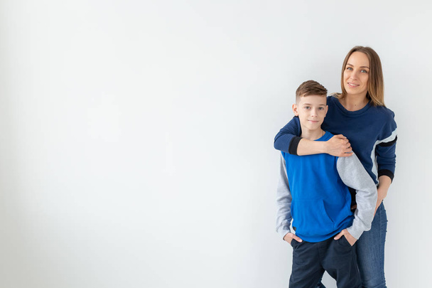 Elternschaft, Familien- und Alleinerziehungs-Konzept - eine glückliche Mutter und ihr Teenager-Sohn lachen und umarmen auf weißem Hintergrund mit Kopierraum - Foto, Bild