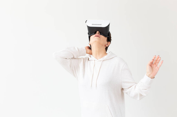 Positive pretty middle-aged woman in a white sweater watching a movie with glasses of virtual reality. The concept of futurism and new technologies. - Photo, Image