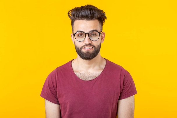 Retrato de un guapo estudiante joven árabe con camisa borgoña posando sobre un fondo amarillo. Concepto de oportunidad para los jóvenes
 - Foto, imagen