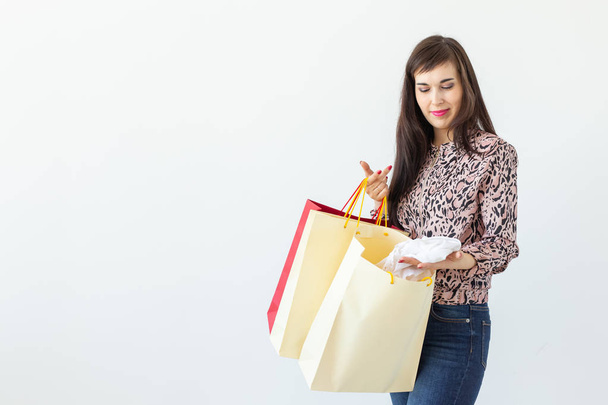 ポジティブな若いスタイリッシュなブルネットの女性は、コピースペースと白い背景にポーズバッグを保持しています。モールでのショッピングコンセプト. - 写真・画像