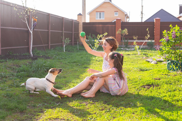 Niña en vestido rosa con madre y gato russell terrier perro tendido en la hierba
. - Foto, Imagen