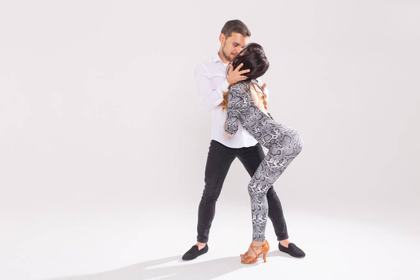 Νεαρό ζευγάρι που χορεύει κοινωνική Λατινική Χορός bachata, merengue, salsa. Δύο κομψότητα πόζα σε λευκό φόντο - Φωτογραφία, εικόνα