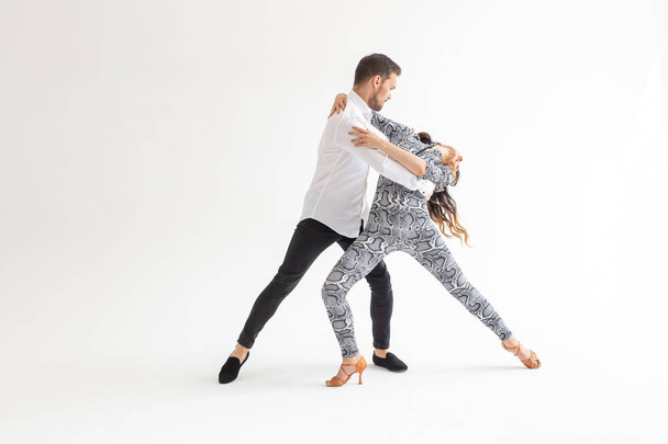 Νεαρό ζευγάρι που χορεύει Λάτιν χοροί Μπατσάτα, μερένγκ, σάλσα, κιζόμπα. Δύο κομψότητα ποζάρει σε λευκό φόντο με χώρο αντιγραφής - Φωτογραφία, εικόνα