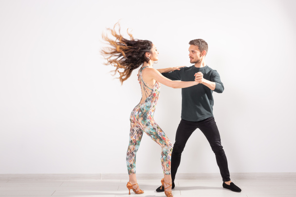 Молодая пара танцует латинский танец бачата, меренге, сальса, кизомба. Две элегантности на белом фоне с копировальным пространством
 - Фото, изображение